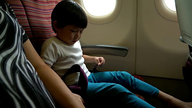 安全概念小男孩在飞机上飞行时系好安全带。视频下载