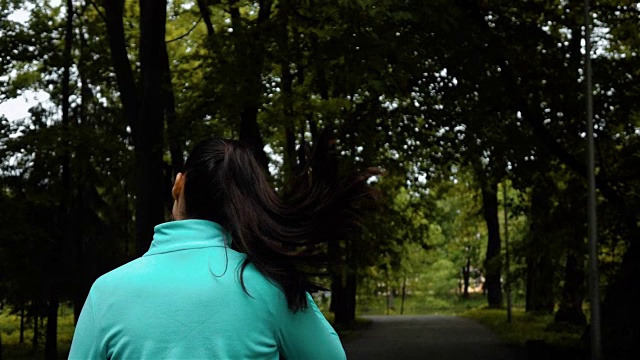 快乐的运动女人在小耳机户外在公园视频素材