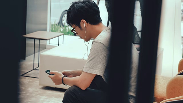 亚洲男人在沙发上玩手机。视频素材