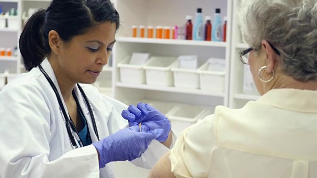 亚洲药剂师或医生在老年妇女接受流感疫苗后给她贴上绷带视频下载