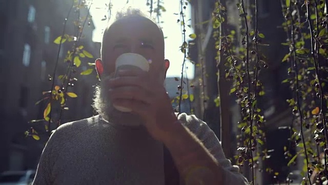 英俊的胡子男人在户外喝着美味的咖啡视频素材