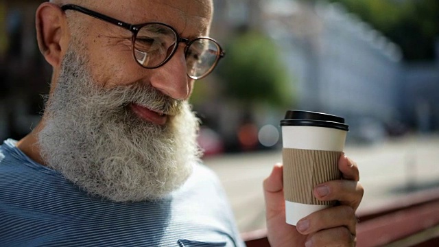 戴眼镜的老先生在户外喝咖啡视频素材