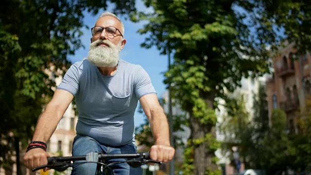 一个深思熟虑的大胡子男人在街上骑着自行车视频素材