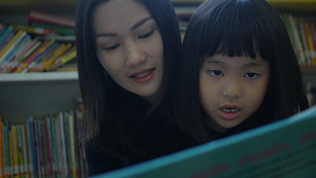 亚洲妇女和女孩在图书馆看书视频素材