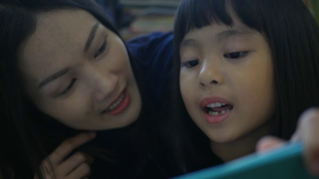 亚洲妇女和女孩在图书馆看书视频素材