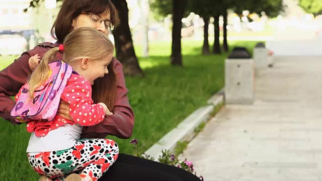 一个小女孩跑向坐在长凳上的妈妈。视频素材