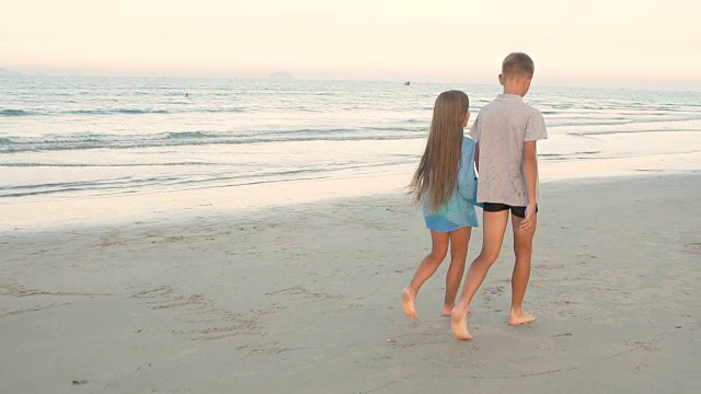 8 - 10岁的小男孩和小女孩在海滩上散步视频下载