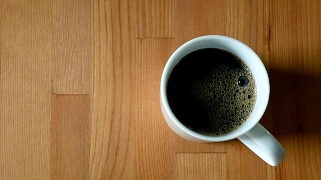 黑咖啡从瓶子里倒进木桌上的杯子里视频素材