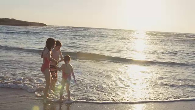 三个孩子一起在沙滩上玩视频素材