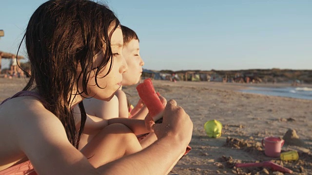 三个孩子在海滩上吃西瓜视频素材