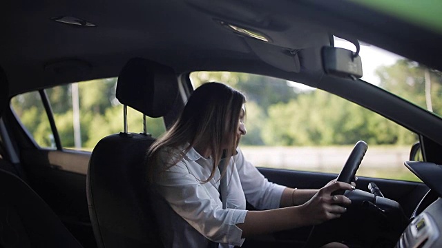 年轻的女商人坐在车里，一边打电话一边调情视频素材
