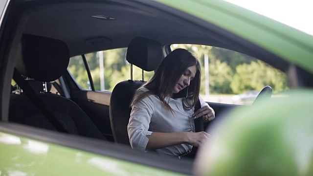 年轻的女商人坐在车里，一边打电话一边调情视频素材