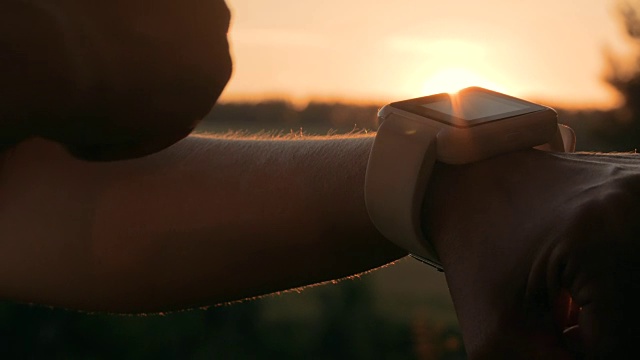 日落时分，一名女子在森林里使用智能手表视频下载