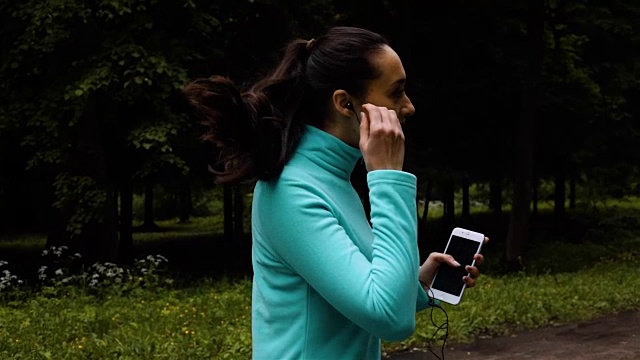 快乐的运动女人戴着耳机在户外柏油路上奔跑视频素材