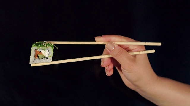 女孩拿着筷子在黑色的寿司。铜视频素材