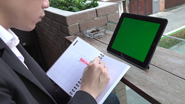4k:商人肩拍使用平板电脑绿色屏幕写笔记视频素材