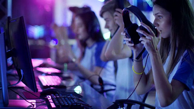 青少年游戏玩家准备参加电子竞技比赛，戴上他们的耳机。比赛场地/网吧在霓虹灯下看起来很酷。视频素材