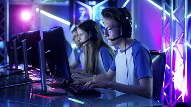 青少年玩家团队在多人电脑游戏中玩电子竞技比赛。队长通过麦克风发出指令，试图在战略上赢得比赛。视频素材