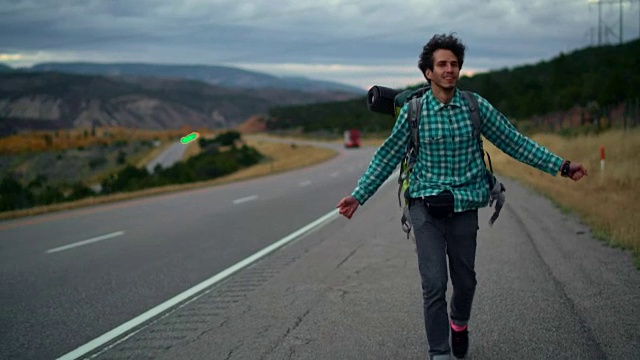 30岁的年轻人，旅行者，背着背包在美国科罗拉多州的高速公路上行走。视频购买