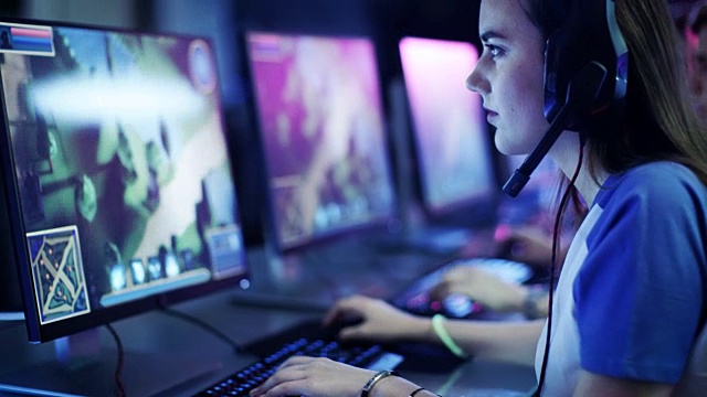 职业女性玩家在她的电脑上玩MMORPG/策略电子游戏。她参加网络游戏比赛，在家里玩，或在网吧玩。她戴着游戏耳机。视频下载