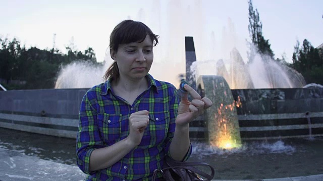 一个女人晚上在喷泉旁玩指尖陀螺视频素材