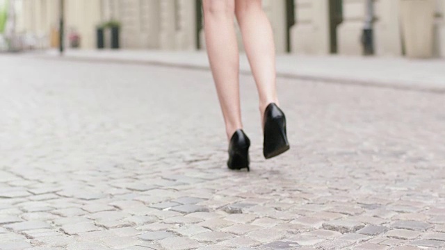年轻女子穿着高跟鞋走在城市里。靠近腿视频素材