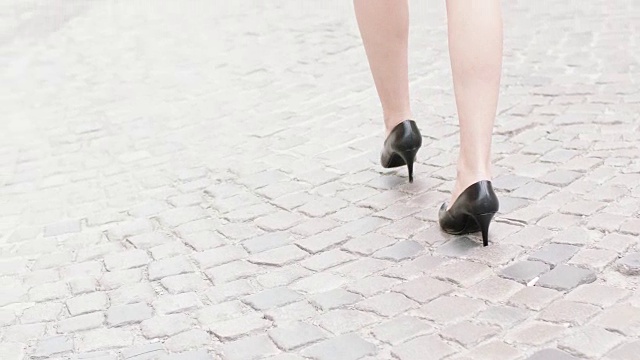 年轻女子穿着高跟鞋走在城市里。靠近腿视频素材