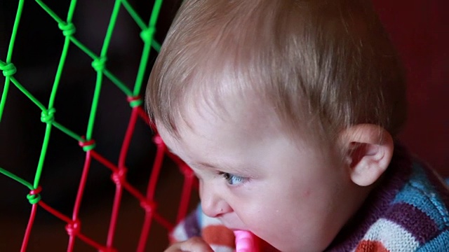 一个婴儿咀嚼粉红色塑料玩具的特写视频下载