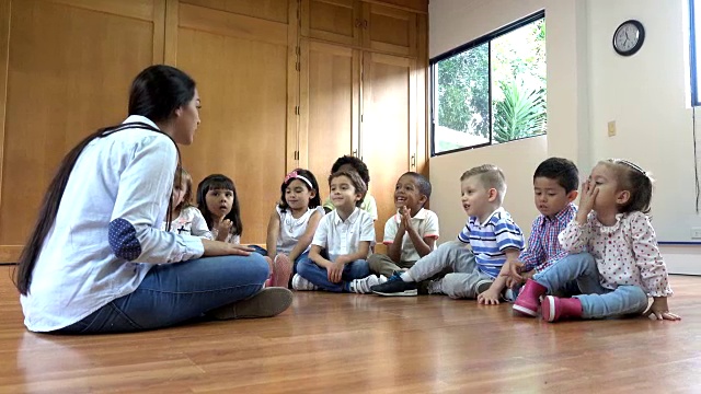 幼儿园老师坐在地板上和她的班级讨论一本书视频素材