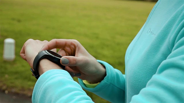 在公园里使用智能手表健身追踪器的女性跑步者视频素材