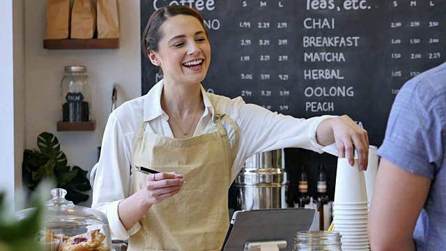 友好的女咖啡师在咖啡馆帮助男性顾客视频素材