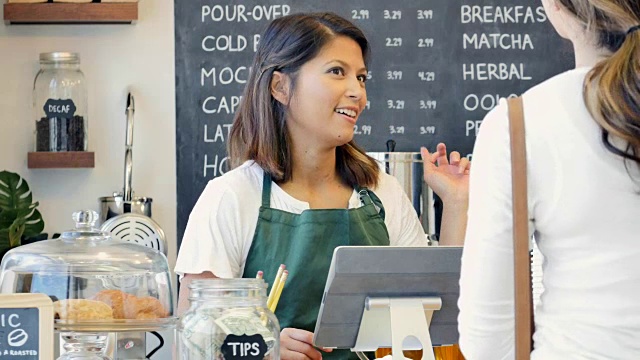 友好的中年亚洲女性咖啡师帮助女性客户与她的订单视频素材