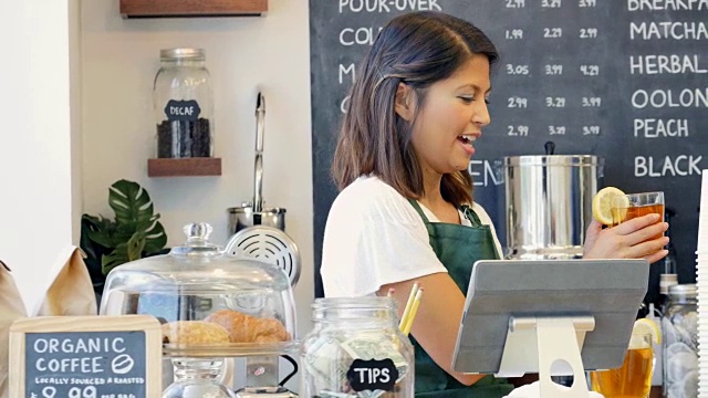 在一家当地的咖啡店里，一位漂亮的女咖啡师正在为一位女顾客点单视频素材