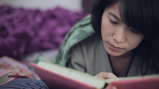 东亚女大学生在床上学习。视频下载