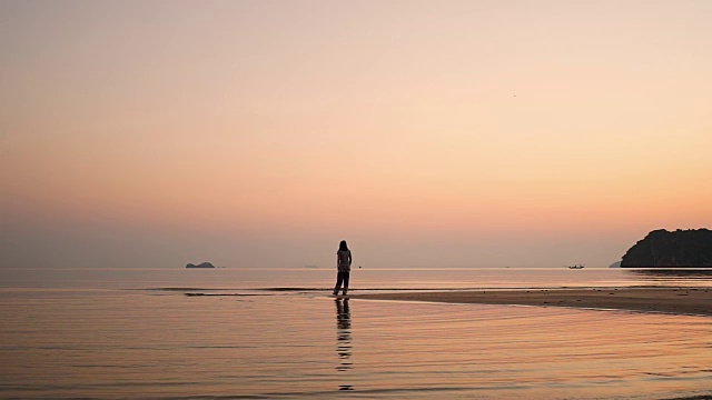 年轻的亚洲女人在日出的海滩上散步。视频素材