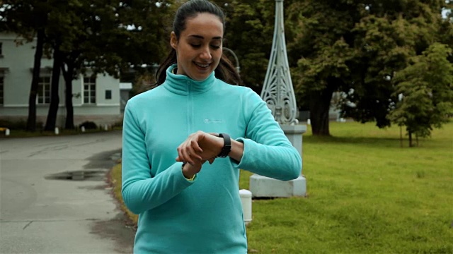 女性跑步者使用智能手表健身追踪器在绿色秋天的森林视频素材