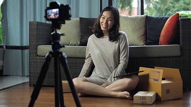 亚洲女性博主用相机记录视频，并在家庭视频博客上谈论视频下载