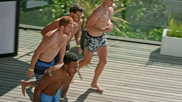 三个男人在一个炎热的一天跳进游泳池派对的游泳池视频素材