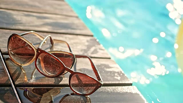 两副太阳镜在泳池边晒太阳视频素材