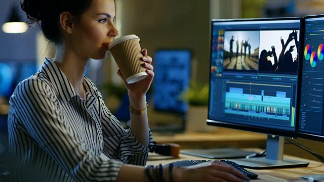 女性视频编辑在她的个人电脑上使用素材和声音。她工作到很晚，喝咖啡。她的办公室是现代创意Loft工作室。视频素材