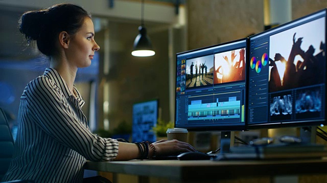 女性视频编辑在她的个人电脑上使用素材和声音。她的办公室是现代创意Loft工作室。视频素材