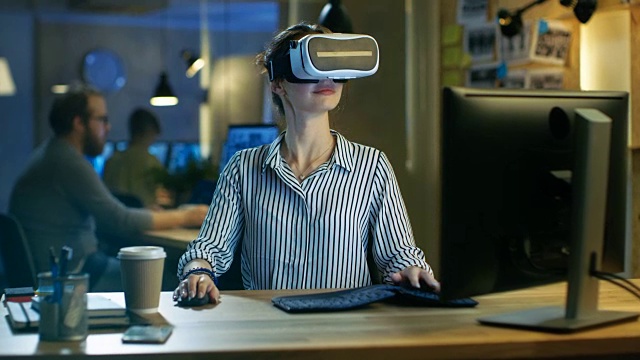 美丽的女性虚拟现实工程师/开发者佩戴VR头戴创造内容。她在一家创意设计师工作室工作。视频素材