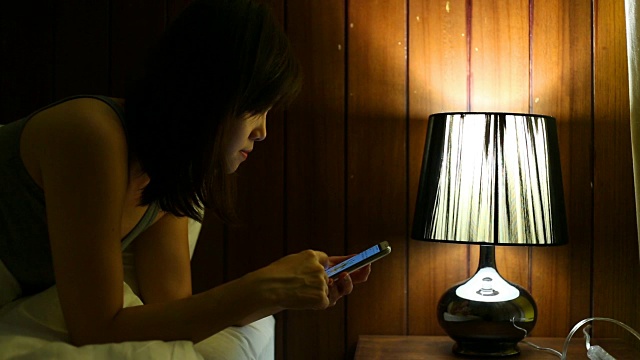 女人在床上用智能手机视频下载