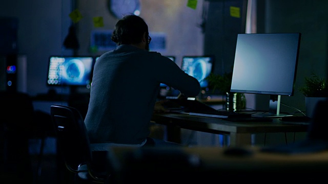 一名手机应用程序开发人员一大早坐在办公桌前开始工作，他独自一人在办公室里。视频素材