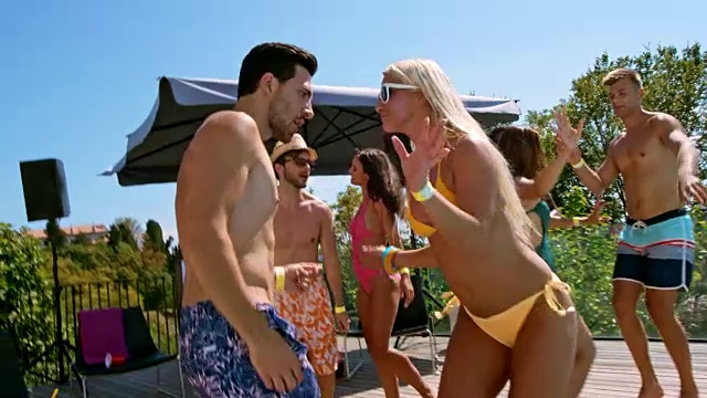 SLO MO穿着泳衣的男人和女人在一个热天的游泳池聚会上跳舞视频素材