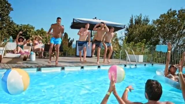 在泳池派对上，四名男子一起跳进泳池，他们的朋友为他们欢呼视频素材