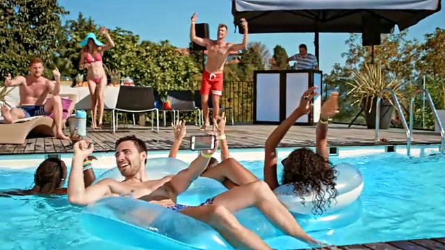 人们在游泳池派对上玩得很开心，在炎热的一天跳舞和游泳视频素材