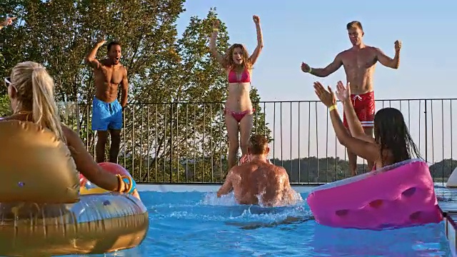 日落时分，一名红发男子在泳池派对上跳入水中视频素材