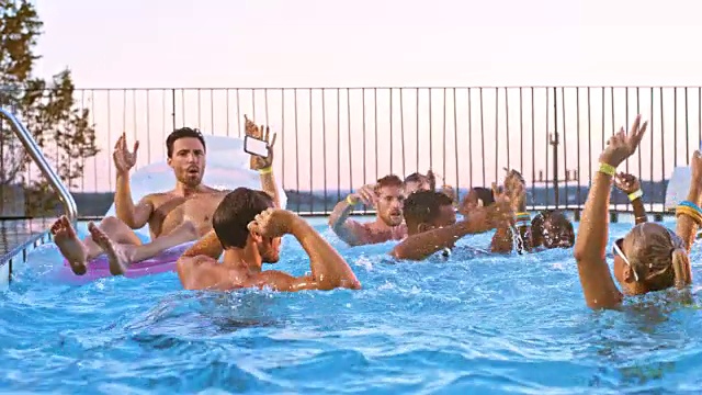 日落时分，人们在游泳池聚会上在水里蹦蹦跳跳视频素材