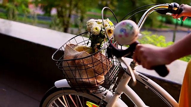 一个不认识的女人骑着一个篮子和花的城市自行车的特写。替身。Slowmotion视频素材